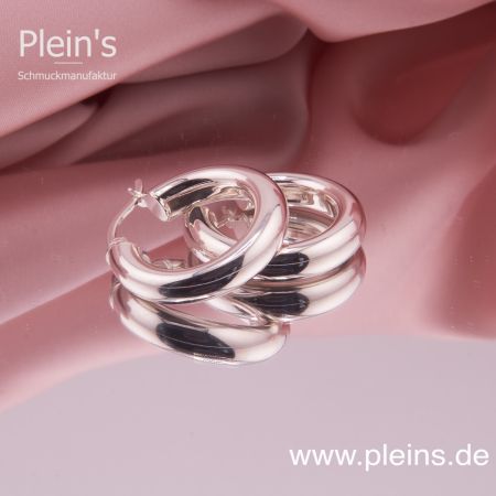 Detailaufnahme der hochglanzpolierten Silber Creolen, liegend auf einer glatten Oberfläche.